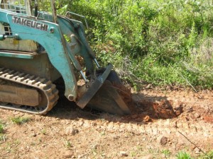 Takeuchi with attachment digging a contour ditch