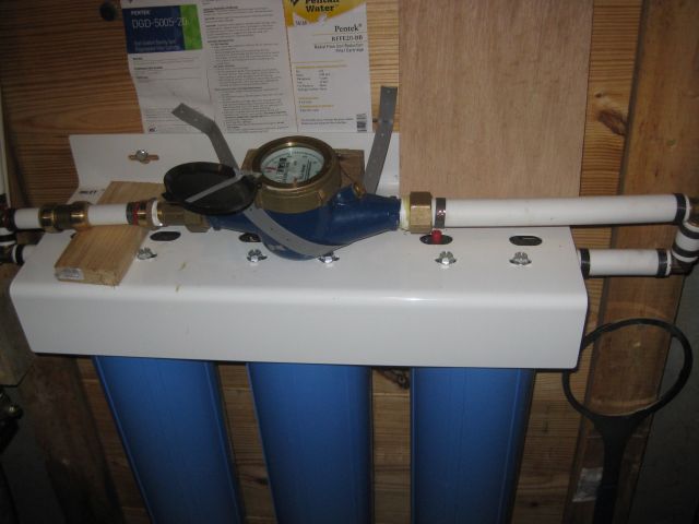 the new water meter is secured on top of the filter assembly.  1" pex from filter then 3/4" pex to house